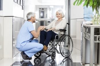 doctor kneeling with elderly woman in wheelchair
